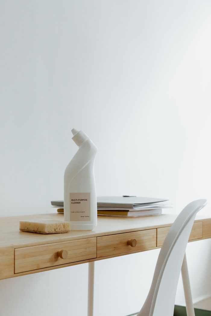 who-we-are A tidy, well-arranged home office desk with a cleaning bottle and sponge, highlighting simplicity and practicality.